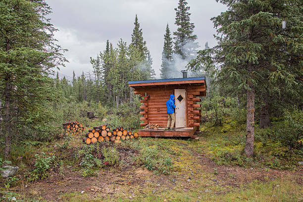 istock One Man at Log Cabin in the Forest 600996494