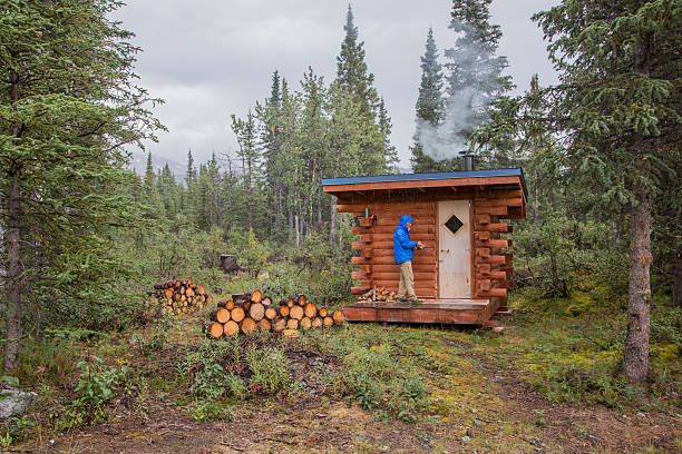 istock One Man at Log Cabin in the Forest 600996532