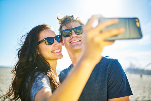 istock happy couple taking romantic selfie on beach with bright sun 600997592