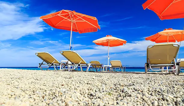 Orange beachchairs on a beach together with umbrellas