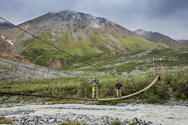 istock Backpackers hiking on a Suspension Bridge across River in Alaska 601002584