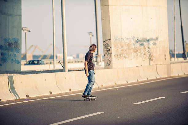 Professional skateboarder riding a skate over a city road bridge, through urban traffic. Free ride skateboards