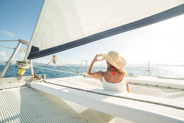 Woman on sailing boat makes heart shape finger frame