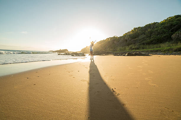 istock Distant person arms outstreched on beach at sunrise 601005850