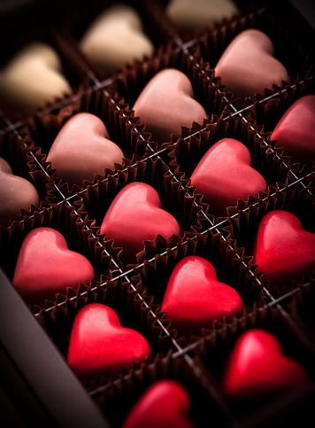 Pralines assortment group heart shaped closeup gradually colored in luxury brown box package