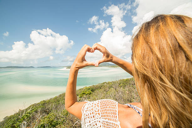 istock Young woman makes heart shape finger frame towards Hill Inlet 601008190