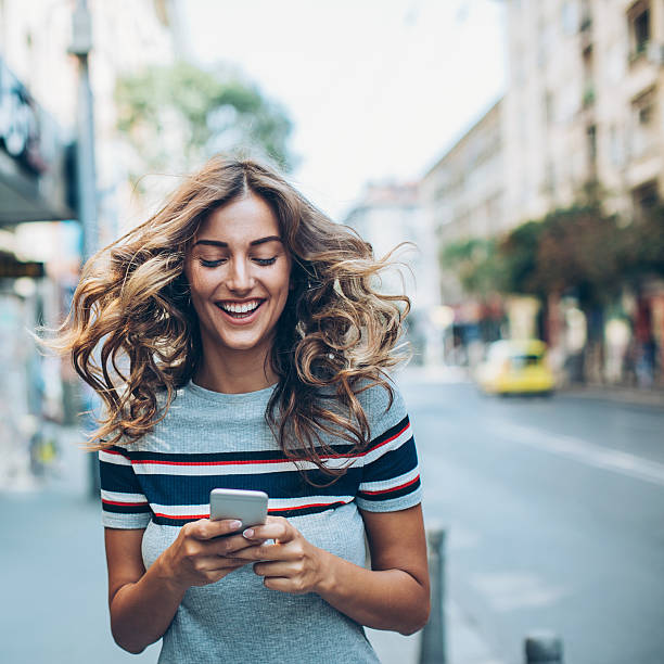 mujer con prisa enviando mensajes de texto en la calle - freedom on the phone urgency telephone fotografías e imágenes de stock