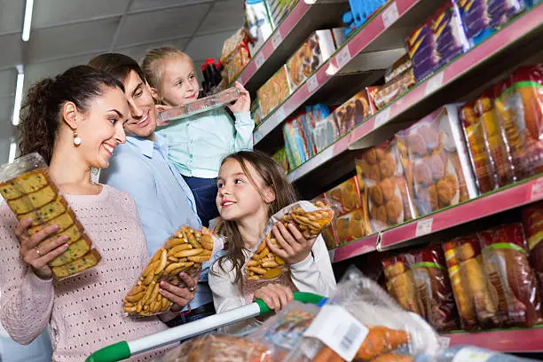 Customers with small children purchasing shortcakes in hypermarket and smiling