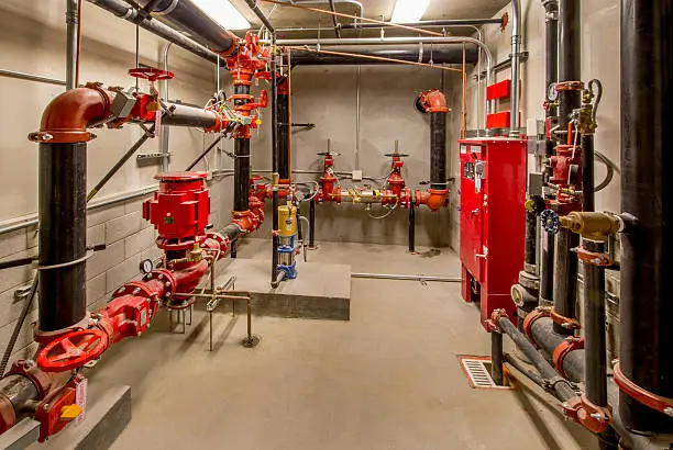 Enclosed fire control system with cast iron pipe, control panel, pumps, and valves.
