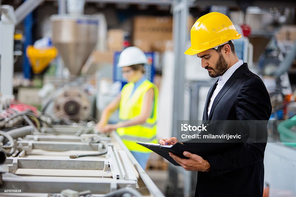 Young quality inspector checking production line Factory. Shallow DOF. Developed from RAW; retouched with special care and attention; Small amount of grain added for best final impression. 16 bit Adobe RGB color profile. Quality Control Stock Photo