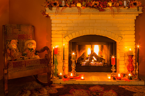 A cozy old fashioned brick fireplace burns and is surrounded by candles and two scarecrow dolls sitting in a rocking chair. This all reminds us of home and the holidays.