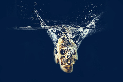 human skull drop into water with splash on black background