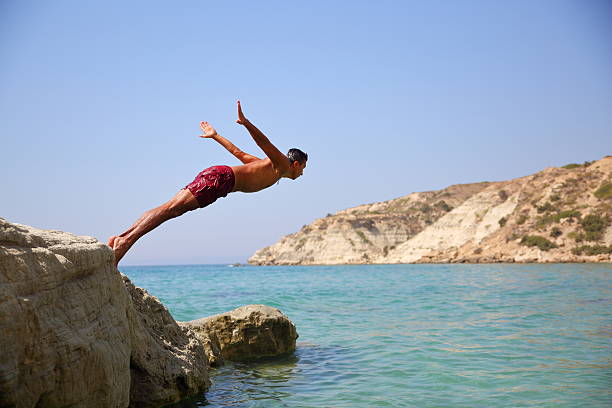 young man diving - salto desde acantilado fotografías e imágenes de stock