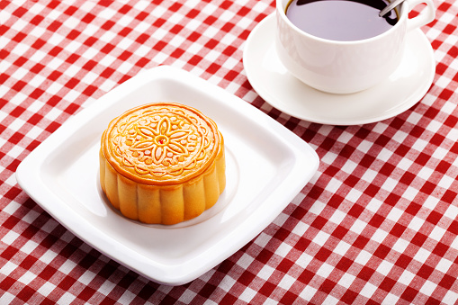 Chinese mid autumn festival foods. Traditional mooncakes on table setting with cup.