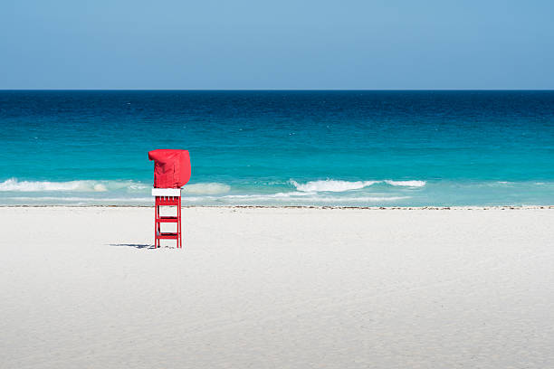 Empty red Lifeguard Chair on the beach in front of beautiful turquoise water, Cancun, Mexico.