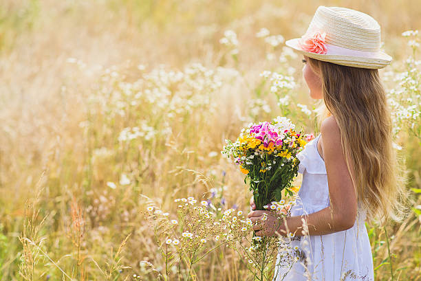 istock Cute female kid with flowers on meadow 601110814