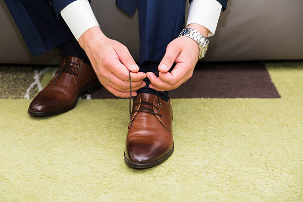 istock Man in suit sitting on couch and tying shoelaces 601120356