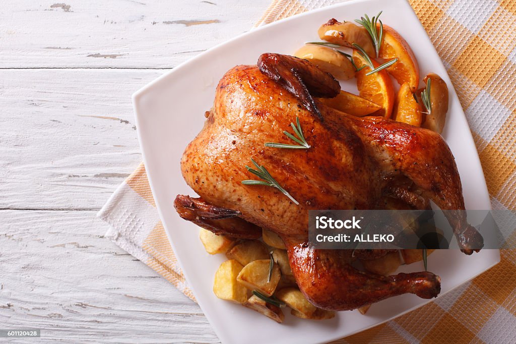 baked whole chicken with oranges on plate. horizontal top view baked whole chicken with oranges and potatoes on a plate. horizontal view from above Turkey Meat Stock Photo