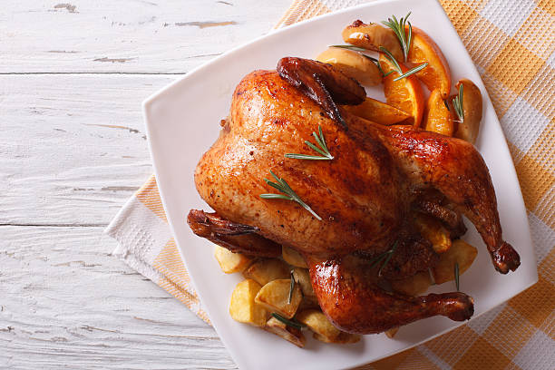 запеченная целая курица с апельсинами на тарелке. горизонтальный вид сверху - chicken roast стоковые фото и изображения