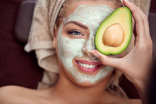 Avocado facial mask portrait of a young woman applying natural avocado mask on her face women facial mask mud cucumber stock pictures, royalty-free photos & images