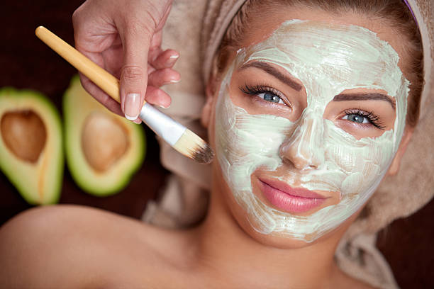 Facial Mask green avocado mask being applied at a beauty spa women facial mask mud cucumber stock pictures, royalty-free photos & images