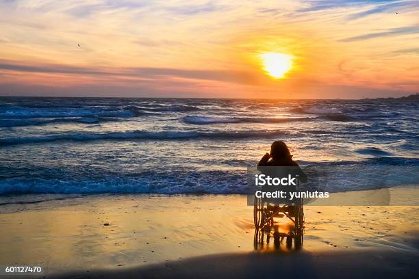 Sunset Makes Sightseeing On The Beach A Woman On Wheelchair Stock Photo - Download Image Now