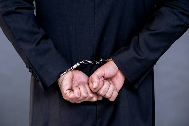 istock suited business man in handcuffs behind over gray background 601128052