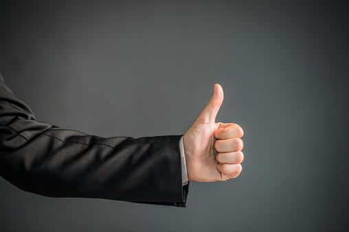 Businessman thumbs up posing, Nonverbal communication. Like, OK, perfect, good job, praise, satisfied, thumb up gesture of businessman over black background