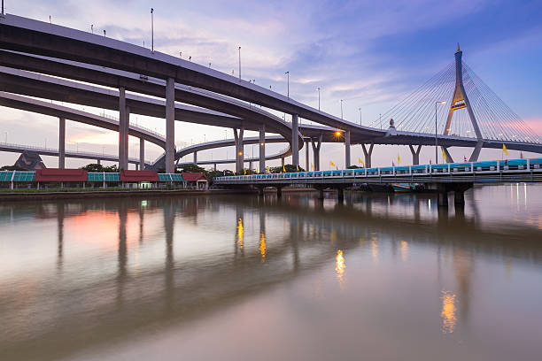 pôr do sol sobre ponte suspensa conectam-se a rodovia intercambiada - bridge bangkok suspension bridge river - fotografias e filmes do acervo