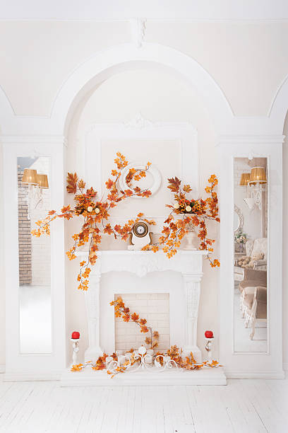 istock White classical fireplace in large hall with autumn decoration 601134344