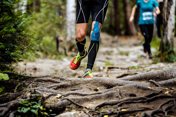 running marathon runner in forest - kinesio imagens e fotografias de stock