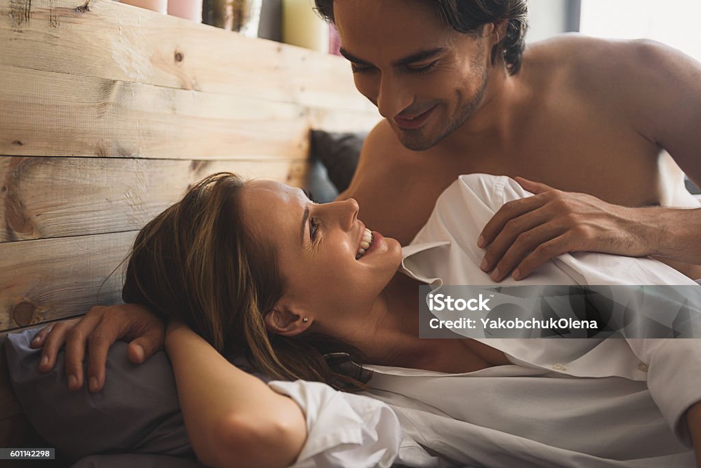 Cheerful couple awaking and looking at each other Affectionate couple lying in bed and looking at each other Activity Stock Photo