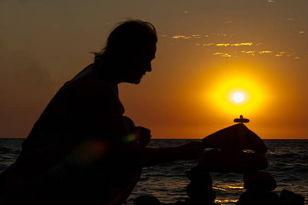 istock woman on the beach building a castle from a pebble 601142778