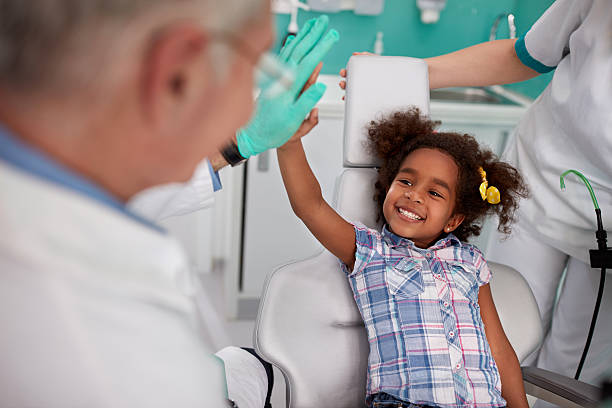 Lovely kid with dentist after repairing teeth Lovely kid in dental chair with dentist satisfied after repairing teeth pediatric dentistry stock pictures, royalty-free photos & images