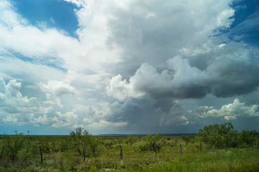 landscape in western Texas with sky, clouds, pending storms and Mesquite trees