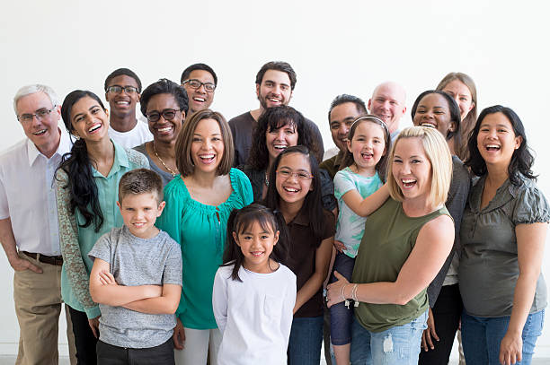 Diverse Family Group A multi-ethnic group of multiple generations are standing together for a family reunion. They are happily laughing and smiling while looking at the camera. family reunion stock pictures, royalty-free photos & images