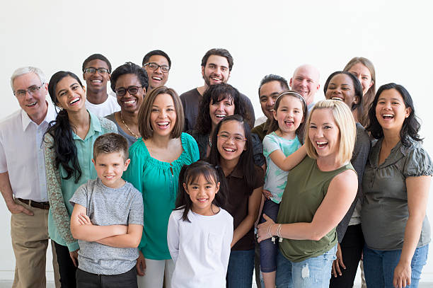 Diverse Family Group A multi-ethnic group of multiple generations are standing together for a family reunion. They are happily laughing and smiling while looking at the camera. family reunion celebration stock pictures, royalty-free photos & images