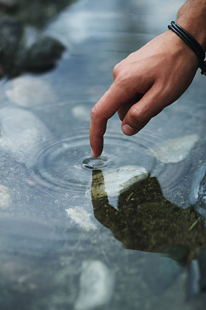 istock finger of man touching stream 601155258