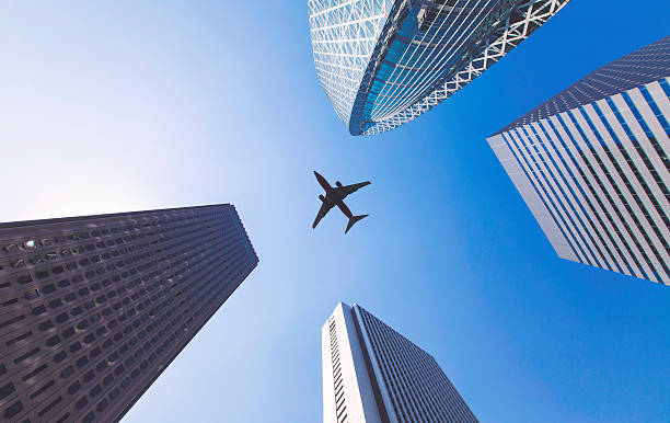 istock Airplane flys between tall city buildings 601158634