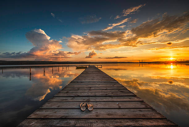 pequeña muelle y barco en el lago - sunset sea tranquil scene sunrise fotografías e imágenes de stock