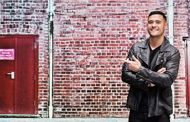 istock Smiling man in front of brick wall and pointing 601362166