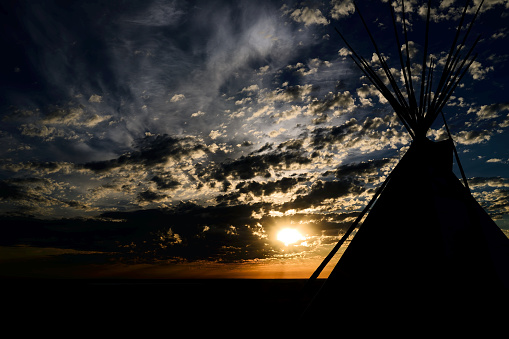Landscape featuring a sunrise with a silhouette of a teepee.