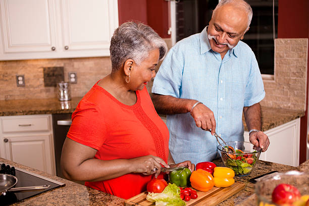 happy senior adult couple cooking together in home kitchen. - cooking senior adult healthy lifestyle couple imagens e fotografias de stock