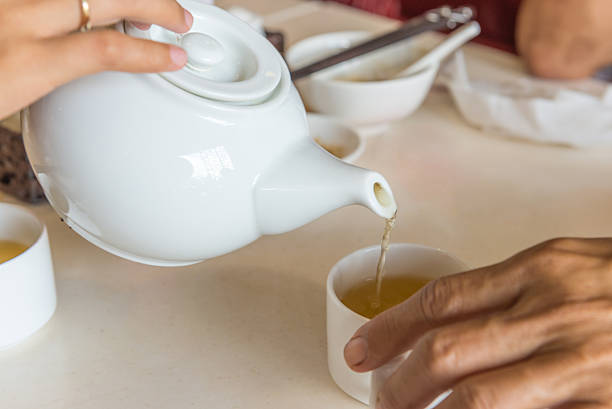 istock Females hand pouring tea from white teapot into a cup 601372564