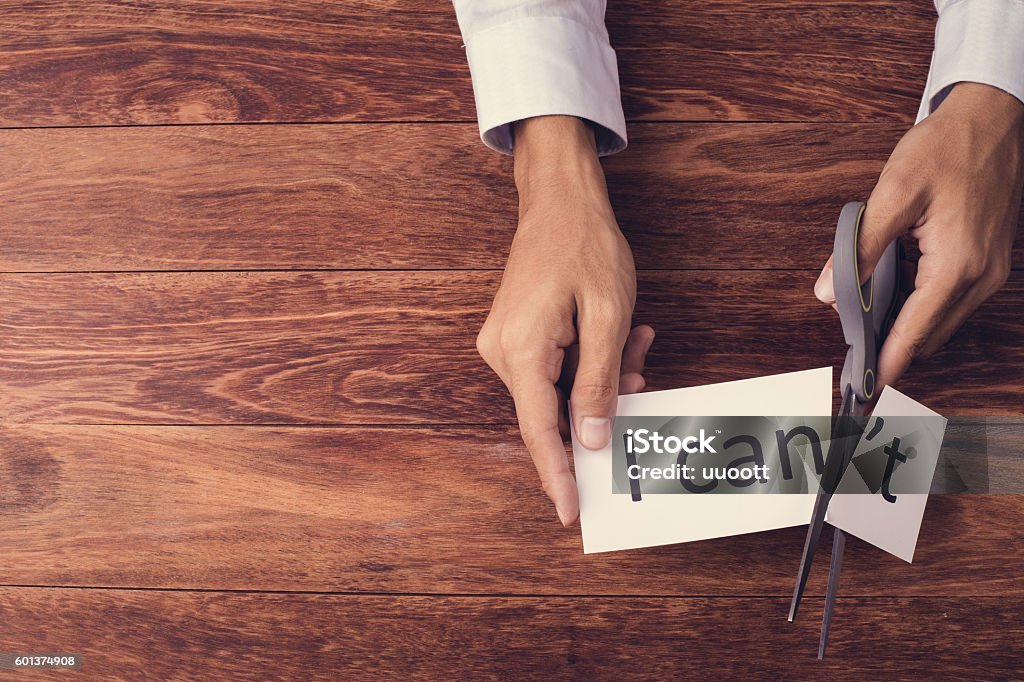 Cutting word "I can't" flat lay Businessman cutting word "I can't" on wooden background. Composition of flat lay and copy space for text. One Person Stock Photo
