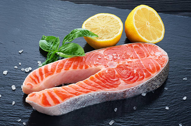 istock Fresh salmon with lemon and basil on a dark background 601376906