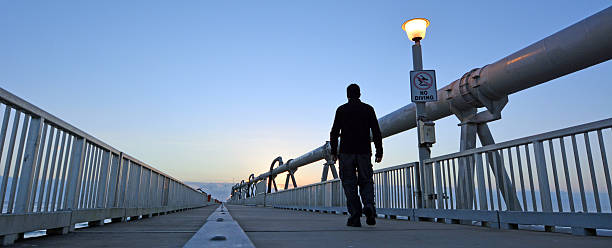 A man walks over the Gold Coast Pier during sunrise  at the Spit in Queensland Australia.