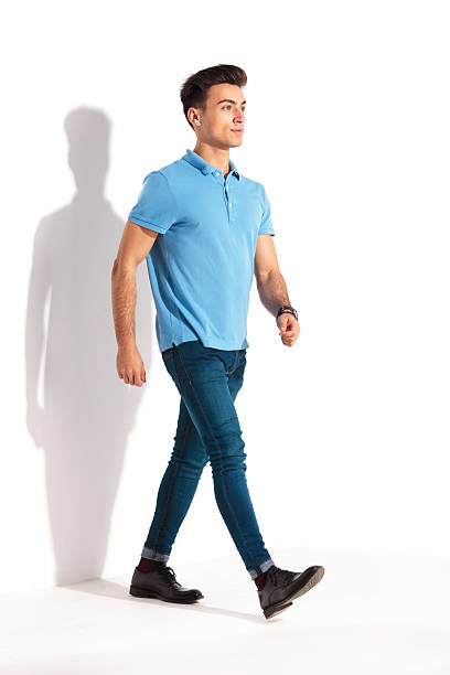 jovem casual confiante em camisa polo e jeans andando - blue polo shirt - fotografias e filmes do acervo