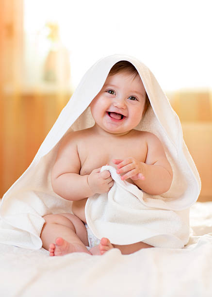 istock Smiling baby girl under towel after bathing 601379232