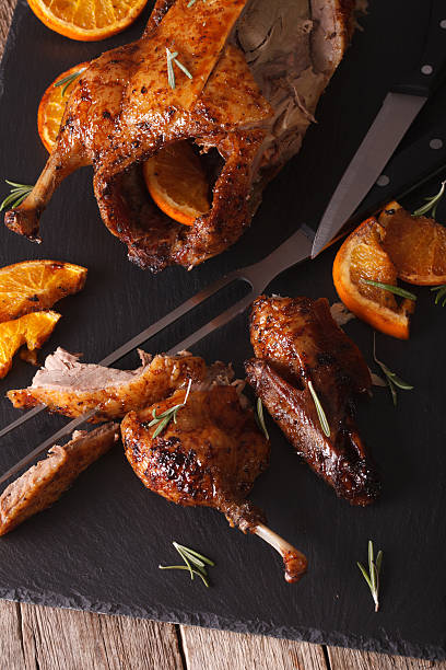istock Cutting baked duck and oranges closeup on a slate board 601380166